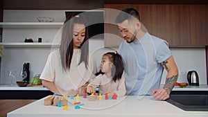 Asian toddler girl playing with sorter puzzle together with parents