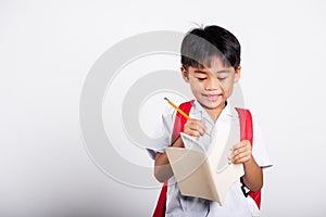 Asian toddler smiling happy wear student thai uniform red pants holding pencil for writers notebook