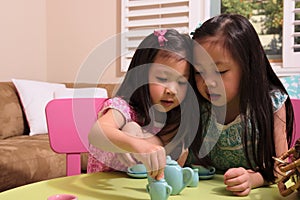 Asian toddlers playing with tea set