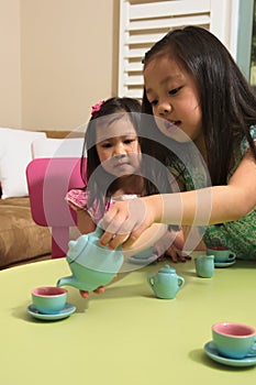 Asian toddlers playing with toy tea set