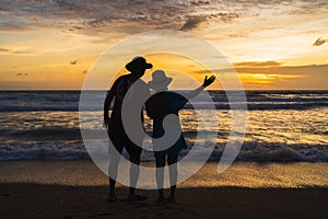 Asian tourist couple taking pictures of sunset at the beach, Beautiful sunset above sea, Colorful Orange and golden sunset sky,