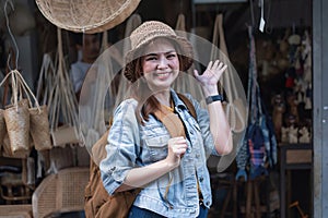 Asian tourist girl shopping, walking in famous local street market looking at beautiful straw hats, happy shopping at