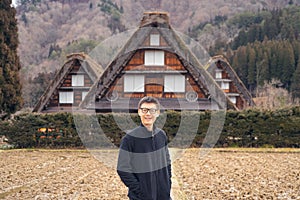 An Asian tourist man at Shirakawago village in travel trip and holidays vacation in sunmer season, Gifu, Japan. Three houses photo