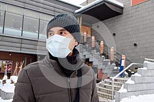 Asian tourist man wearing mask protecting from Coronavirus during winter