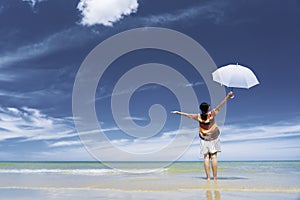 Asian tourist woman with white unbrella relaxing on the beach