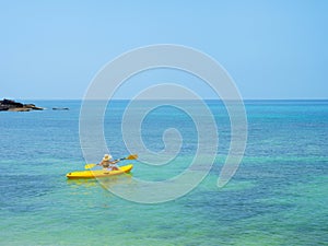 Asian tourist on yellow Kayak boat in tropical island blue sea bright sun in summer. Koh Kood - Thailand