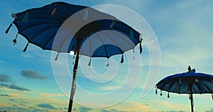 Asian traditional beach sun umbrella in the island of Bali in Indonesia before a vivid blue sunset sky in Summer holidays and