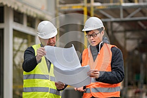 Asian trainee engineer at work on construction site with the senior manager