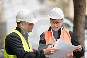 Asian trainee engineer at work on construction site with the senior manager