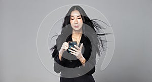 Asian Transgender Woman with long black straight hair, wind blow throw in the Air. Female hold phone against wind storm, feeling