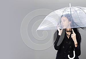 Asian Transgender Woman with long black straight hair, wind blow throw in the Air. Female hold phone and umbrella against wind