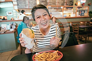 Asian traveler holding fries and hamburger