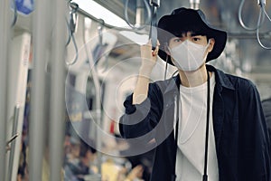 Asian traveler man and camera in skytrain with medical face mask to protection the Covid-19, new normal lifestyle