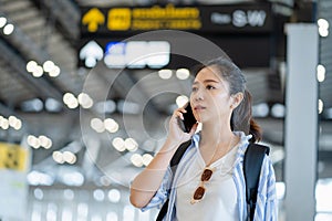 Asian traveler using the smartphone at an international airport on a weekend trip, travel and transportation with technology