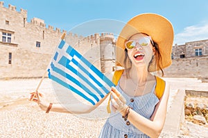 Asian traveler woman with greek flag enjoying great view to the old Knights Grand Master Castle in Rhodes, Greece