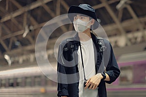 Asian travelers men and camera in train station with medical face mask to protection the Covid-19, new normal lifestyle