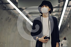 Asian travelers men and camera in train station with medical face mask to protection the Covid-19, new normal lifestyle