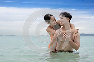 Asian traveller couple playing and sweet togather on the beach between honeymoon day