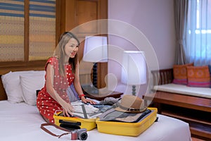 Asian traveller woman packing her travel bag on hotel bed