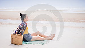 Asian traveller woman sit back and relax on the beach by the sea background on weekend vacation.Concept of happy solo travel