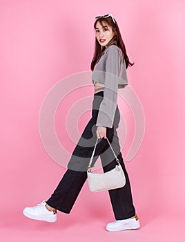 Asian trendy fashionable female hipster teen model in casual crop top street wears jacket sunglasses sneakers holding handbag purs