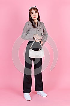 Asian trendy fashionable female hipster teen model in casual crop top street wears jacket sunglasses sneakers holding handbag purs