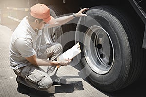 Asian a truck driver holding clipboard his checking safety a truck wheels and tires. semi truck transportation.