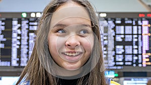 Asian tween girl in front of airport arrivals board