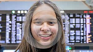 Asian tween girl in front of airport arrivals board