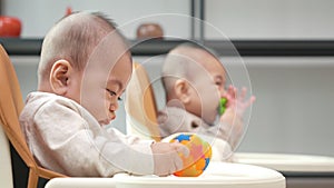 Asian twin babies sitting on safety chair, the chair can use for car seats