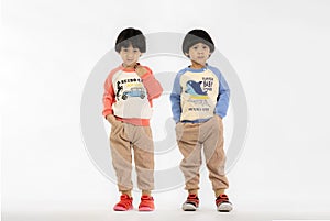 Asian Twins child with dark hair and black eyes isolated on a white background. Photo of adorable young happy twins boy looking at