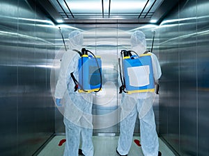 Asian two cleaner men use sanitizing spray for protect covid-19 or coronavirus and bacteria inside elevator or lift from backpack