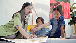 Asian two siblings learning study watercolor paint together at home. Teacher or parent teach student or daughter drawing paint