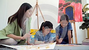 Asian two siblings learning study watercolor paint together at home. Teacher or parent teach student or daughter drawing paint