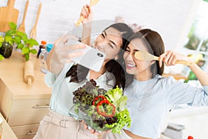 Asian two women wearing sportswear eat healthy foods in kitchen. Young beautiful girl happy and enjoy eating fruits healthy