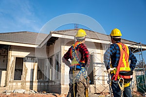Asian two workers wearing fall protection safety clothing  with hooks at construction site. Safety body construction, Working at
