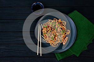 Asian udon noodles with chicken vegetables and teriyaki sauce on a black wooden background. Chinese and Japanese cuisine. Copy