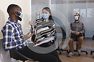 Asian unemployed woman and african american man sitting in lobby area of financial company while talking about career