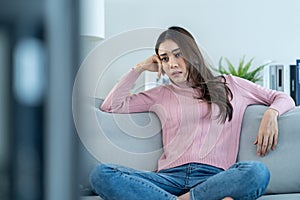 Asian unhappy young beautiful woman watch movie on television at home. Attractive girl feel upset, sit on sofa in living room