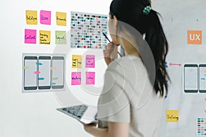 Asian ux designer evaluating app prototypes with color swatches. photo