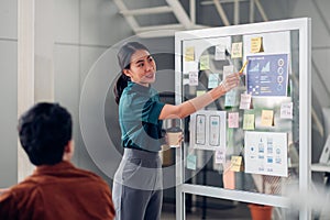 Asian ux developer and ui designer presenting mobile app interface design on whiteboard in meeting at modern office.Creative