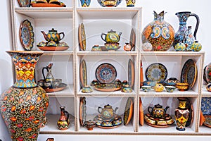 Asian Uzbek handmade ceramic plates and tableware with hand-painted traditional Asian colorful patterns on shelves in