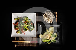 Asian vegan vegetarian food menu on dark background top view. Pack choy stir fry vegetables and rice bawl dish on black table