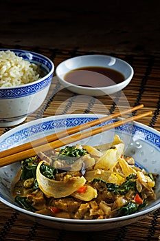 Asian vegetable dish with chopsticks on a bamboo mat, rice and s