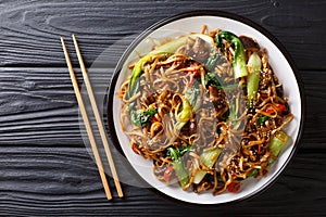 Asian vegetarian food udon noodles with baby bok choy, shiitake mushrooms, sesame and pepper close-up on a plate. horizontal top