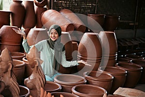 asian veiled woman with hand gesture offering something between pottery
