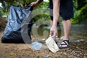Asian volunteer is picking up trash waste rubbish with garbage bag,medical masks of tourists in national park,problem of littering