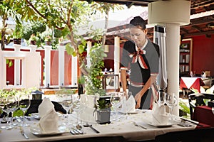 Asian waitress setting table in restaurant