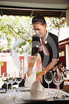 Asian waitress setting table in restaurant