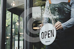 Asian waitress staff woman wearing apron turning open sign board on glass door in modern cafe coffee shop, hotel, cafe restaurant,